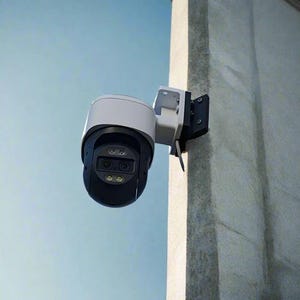 Peut inclure: Une caméra de sécurité blanche et noire montée sur un mur blanc. La caméra a deux objectifs et un dôme blanc.