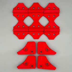 May include: A set of ten red plastic pieces with holes. The pieces are shaped like a combination of a triangle and a rectangle. The pieces are arranged in a grid pattern. There are four additional pieces that are shaped like a triangle with a rounded corner.