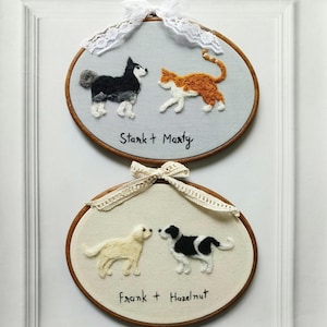 May include: Two embroidered hoops with pet portraits. The top hoop features a black and white dog and an orange and white cat, with the text "Stark + Marty". The bottom hoop shows a golden dog and a black and white dog, with the text "Frank + Hazelnut".