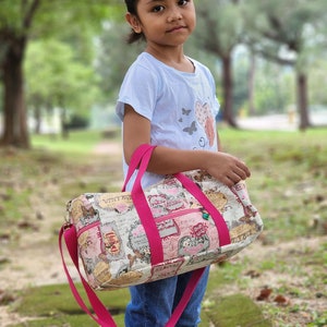 Day-To-Day Duffle Bag Sewing Pattern featuring the small size with a child model. The webbing is hot pink and the adjustable strap feature is shown.