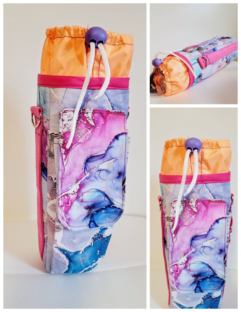 May include: A water bottle holder with a vibrant abstract design in shades of blue, purple, and white. The holder features a drawstring closure with a purple bead, a pink trim, and a side pocket. The top is orange.