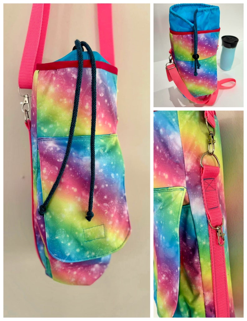 May include: A water bottle carrier with a vibrant galaxy print in shades of pink, blue, green, and yellow. It features a drawstring closure, a small front pocket, and a bright pink adjustable shoulder strap. The carrier is designed to hold a water bottle.