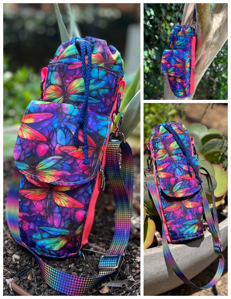 May include: A colorful crossbody bag with a dragonfly pattern in shades of purple, blue, pink, and green. The bag has a drawstring closure, a small front pocket, and a rainbow-colored strap. The interior is lined with a bright pink fabric.