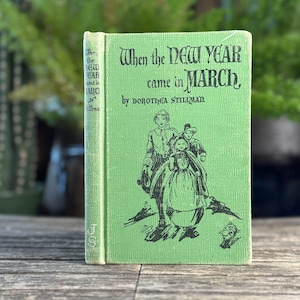 May include: A vintage book titled "When the New Year Came in March" by Dorothea Stillman. The book has a light green cover with black illustrations and text. The spine is also light green with the author's name and title.