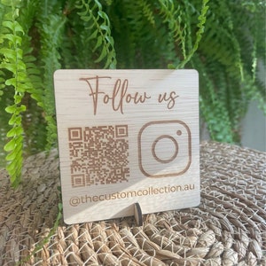 May include: Wooden sign with the text "Follow us" and a QR code and Instagram logo. The text "@thecustomcollection.au" is below the logo.