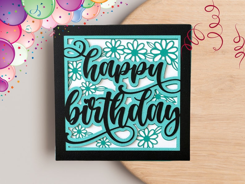 May include: A teal blue card with a black border and the words "happy birthday" in black script. The card is decorated with white flowers.