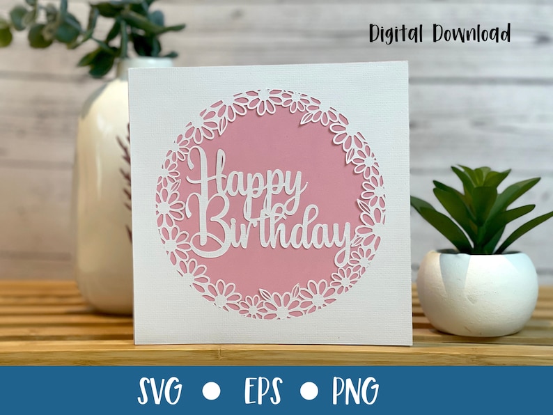 May include: A white card with a pink circle in the center. The circle has a white floral design around the edge and the words "Happy Birthday" in white script inside.