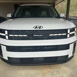 Puede incluir: SUV Hyundai Palisade Calligraphy blanco con detalles negros y una parrilla negra. Se muestra la parte delantera del vehículo con el logotipo de Hyundai y la palabra "Calligraphy" en la parrilla.