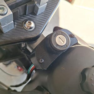 May include: A close-up shot of a motorcycle ignition switch. The black switch has the words "OFF" and "IGNITION" printed on it. The keyhole is visible, and wires are connected to the switch.