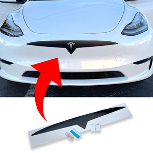 Könnte beinhalten: Eine schwarze Vinylfolie für die Front eines Tesla Model Y. Die Folie bedeckt den vorderen Kühlergrill und hat das Tesla-Logo ausgeschnitten. Die Folie wird mit einem Rakel und einer Anleitung zur Anwendung geliefert.