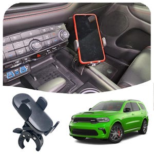 Könnte beinhalten: Ein schwarzer Handyhalter mit einer Klemmbefestigung, der für die Befestigung an der Lüftung eines Autos konzipiert ist. Der Halter ist im Innenraum eines Autos zu sehen, mit einem Smartphone im Halter. Ein grüner Dodge Durango ist ebenfalls auf dem Bild zu sehen.