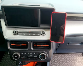 Puede incluir: Un teléfono inteligente negro en una funda roja está montado en el tablero de instrumentos de un automóvil. El tablero del automóvil tiene una pantalla táctil, botones de control de clima y una radio.
