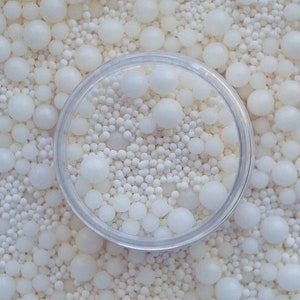 以下が含まれることがあります： 白いパールスプリンクルと白いシュガースプリンクルが入った透明なプラスチック容器