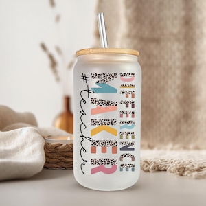 Peut inclure: Un gobelet en verre dépoli avec un couvercle en bambou et une paille en métal. Le gobelet porte les mots "#teacher MAKE A DIFFERENCE" en différentes couleurs et des motifs léopard. Le gobelet est conçu pour les boissons froides.