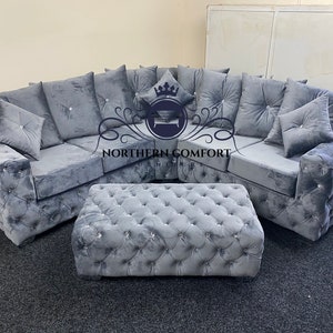 May include: A gray sectional sofa and matching ottoman set. The sofa features a tufted design with crystal-like buttons and plush cushions. The ottoman is rectangular and also tufted. The logo "NORTHERN COMFORT" is visible.