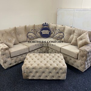 May include: A beige sectional sofa and matching ottoman set. The sofa features a tufted design with decorative pillows and crystal accents. The ottoman is square and also tufted. The logo "NORTHERN COMFORT FURNITURE" is visible.