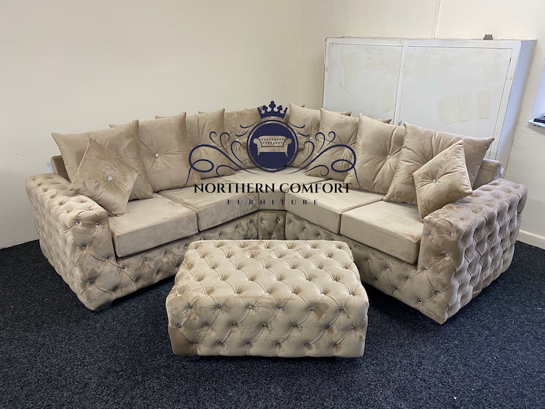 May include: A beige sectional sofa and matching ottoman set. The sofa features a tufted design with decorative pillows and crystal accents. The ottoman is square and also tufted. The logo "NORTHERN COMFORT FURNITURE" is visible.