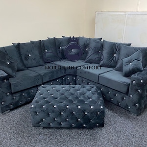 May include: A dark gray sectional sofa and matching ottoman set. The sofa features a tufted design with crystal-like accents and plush cushions. The ottoman mirrors the sofa's design, creating a cohesive living room furniture set.