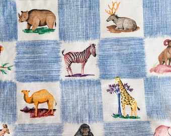 Puede incluir: Una tela a cuadros azules y blancos con una variedad de ilustraciones de animales, incluyendo un rinoceronte, una cebra, una jirafa, un camello, un gorila, un elefante, un canguro y un loro.