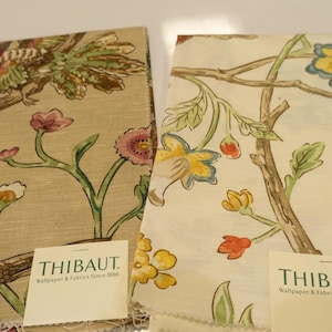 May include: Two fabric swatches with floral and bird patterns. One features a bird perched on a branch with pink flowers. The other has yellow and blue flowers with a butterfly. Both have the "THIBAUT" label.