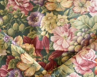 Könnte beinhalten: Nahaufnahme eines floralen Stoffes mit dunkelgrünem Hintergrund. Der Stoff zeigt ein Muster aus großen, farbenfrohen Blumen in Rosa-, Gelb- und Lilatönen sowie grüne Blätter und Früchte. Das Design ist detailliert und aufwendig.
