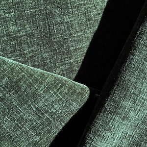 May include: Close-up of a dark green fabric with a textured weave. The fabric is folded over itself, creating a sharp crease.