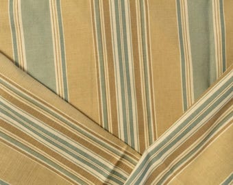 Puede incluir: Primer plano de una tela con rayas verticales en tonos beige, azul claro y marrón. La tela está doblada, revelando el patrón y la textura. Las rayas varían en ancho, creando un diseño visualmente interesante.