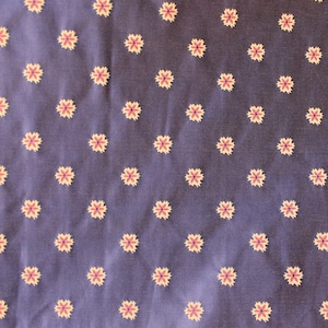 May include: A dark blue fabric with a repeating pattern of small, white flowers with a red center.