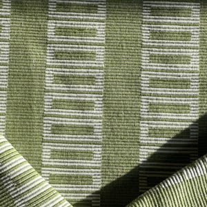 Puede incluir: Primer plano de una tela rayada verde y blanca con un patrón tejido. La tela tiene un brillo sutil y una textura suave.