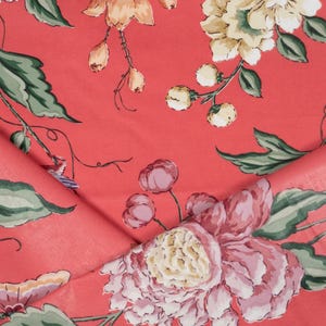 May include: A coral-colored fabric featuring a floral pattern with large pink and cream-colored peonies, green leaves, and small butterflies. The design includes thin, winding stems and delicate buds scattered across the vibrant coral background.