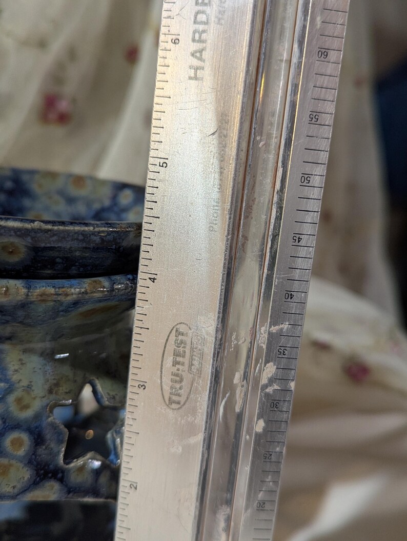 K&ouml;nnte beinhalten: Ein Metalllineal mit dem Text "TRU-TEST" und "HARDE" befindet sich neben einer blauen Keramikschale mit sternf&ouml;rmigen Aussparungen. Das Lineal zeigt Messungen in Zentimetern, bis zu 15 cm.