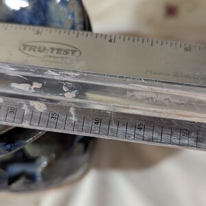 K&ouml;nnte beinhalten: Ein Edelstahl-Lineal mit dem Text "TRU-TEST" liegt &uuml;ber einer Keramikschale. Das Lineal zeigt Messungen in Zentimetern, von 76 cm bis 127 cm. Die Schale hat eine blaue und braune Glasur.