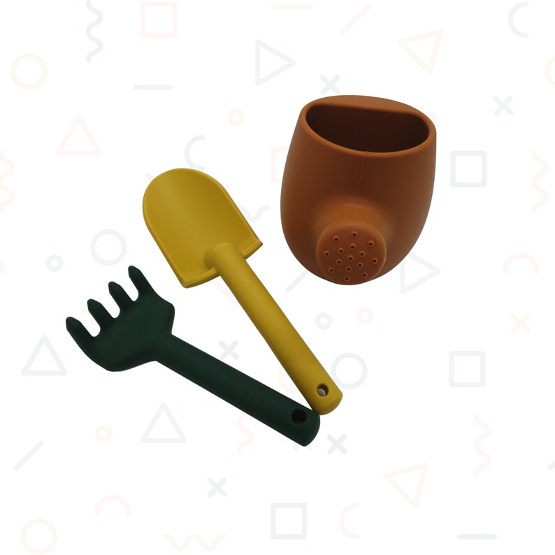 Pu&ograve; includere: Un set di tre attrezzi da giardinaggio colorati: una pala gialla, un rastrello verde scuro e un annaffiatoio marrone. Gli attrezzi sono realizzati in un materiale morbido e sono progettati per il gioco dei bambini. L'annaffiatoio ha un beccuccio con piccoli fori.