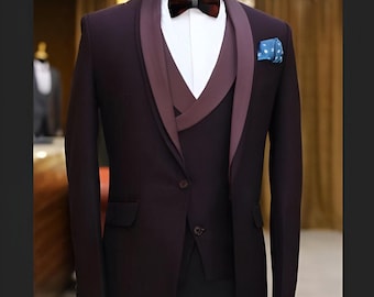 Pode incluir: Um terno de três peças em cor bordô escuro com colar de xale e camisa branca. O terno tem lapela de cetim e um lenço de bolso.