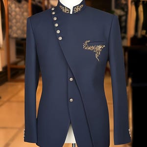 May include: Navy blue suit jacket with an asymmetrical button closure and mandarin collar. The jacket features gold embroidery on the collar and pocket, and silver buttons. The tailored fit and unique design make it a stylish formal wear option.