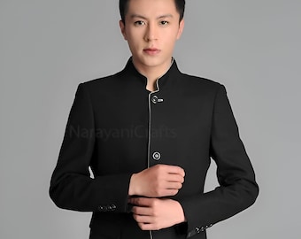 Pode incluir: Um blazer preto com colarinho mandarim e fecho de um único botão. O blazer tem uma guarnição branca em volta do colarinho e punhos.