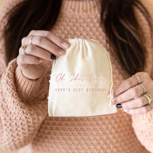 May include: A white cotton drawstring bag with the text "Oh Shit Kit... Evvy's 21st Birthday" printed in pink.