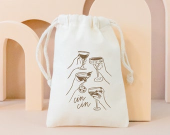 May include: A white drawstring bag with a brown illustration of four hands holding up different glasses of wine. The text "cin cin" is printed below the glasses.