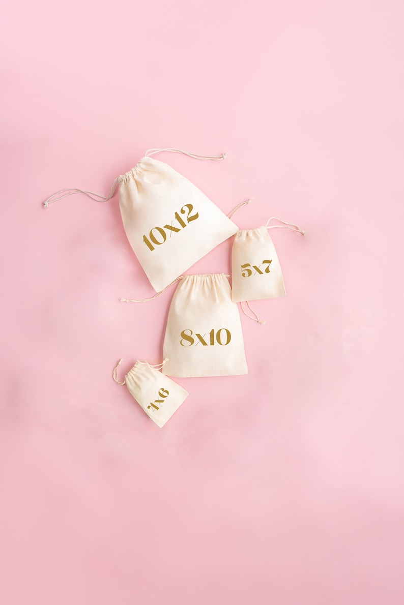 May include: Four white cotton drawstring bags with gold lettering on a pink background. The bags are labeled with different sizes: 10x12, 8x10, 5x7, and 6x8.