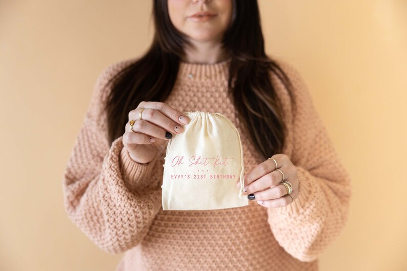 May include: A white cotton drawstring bag with the text "Oh Shit Kit... Evvy's 21st Birthday" printed in pink.