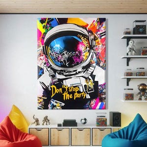 Peut inclure: Une impression sur toile pop art vibrante représentant un casque d'astronaute avec une scène de fête reflétée dans la visière. L'œuvre d'art est placée sur un fond abstrait coloré avec le texte "Don't stop the party".