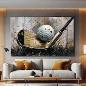 Peut inclure: Œuvre d'art sur le thème du golf représentant une balle de golf posée sur un club de golf. La peinture utilise une palette de couleurs neutres avec des accents dorés et noirs. L'œuvre est affichée au-dessus d'un canapé blanc avec des coussins orange.