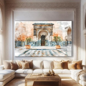 Może przedstawiać: Duży, oprawiony wydruk akwareli przedstawiający zdobiony marokański dziedziniec z kafelkową podłogą, łukowatymi drzwiami i roślinami doniczkowymi. Grafika jest eksponowana nad białą sofą narożną z dekoracyjnymi poduszkami i drewnianym stolikiem kawowym.