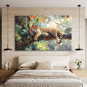 Op de afbeelding: Een rechthoekige wandkunstprint met een gevlekte jaguar die rust op een dikke boomtak te midden van weelderig groen gebladerte en gevlekt zonlicht. Het schilderij toont levendige kleuren van geel, oranje en diepgroen.