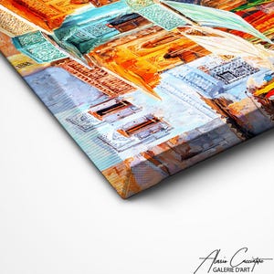 May include: An abstract canvas painting depicting a cityscape with a perspective view. The artwork uses a palette of warm and cool colours, such as orange, blue, and white, with visible brushstrokes and textures. The canvas is angled, showing its side profile.