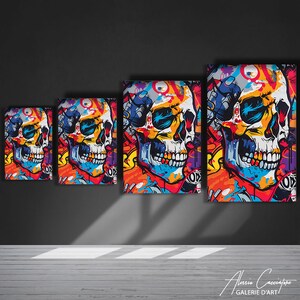 Puede incluir: Cuatro impresiones de lienzo coloridas de una calavera con arte de graffiti. La calavera es blanca con ojos negros y una boca negra. El fondo es una mezcla de colores brillantes, incluyendo rojo, naranja, amarillo, verde, azul y morado.