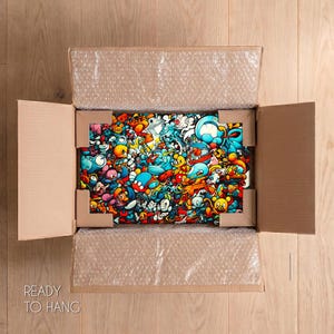 May include: A rectangular wall art piece featuring a dense, colorful collage of cartoon-style characters in shades of blue, orange, red, and yellow, securely packaged inside an open cardboard shipping box with protective bubble wrap and corner guards.