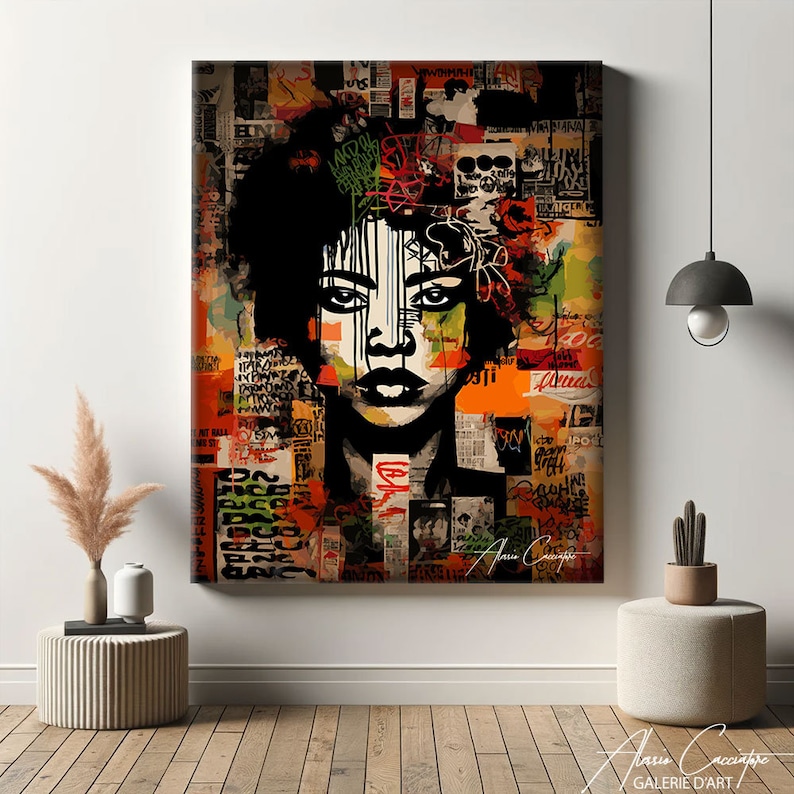 May include: A framed canvas print of a woman's portrait with a black afro and striking features. The background is a collage of text and abstract shapes in orange, green, and red. The artwork has a graffiti-style aesthetic.
