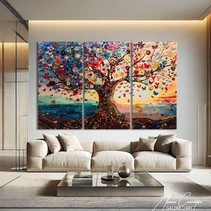May include: A triptych canvas artwork showing a colourful tree adorned with flowers and butterflies. The piece features a brown tree trunk and branches, set against a blue and orange sunset. The art is displayed above a beige sofa.