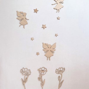 May include: Wooden wall decor featuring three fairies and three flowers. The fairies are flying with their wings spread out. The flowers are simple and have a stem and leaves. The decor is painted in a light wood color.
